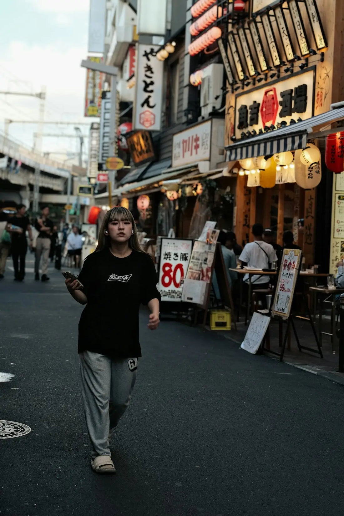 A woman walking down a street next to tall buildings