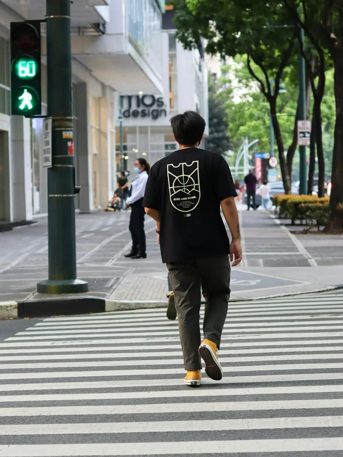 man in black t-shirt and brown pants walking on pedestrian lane during daytime