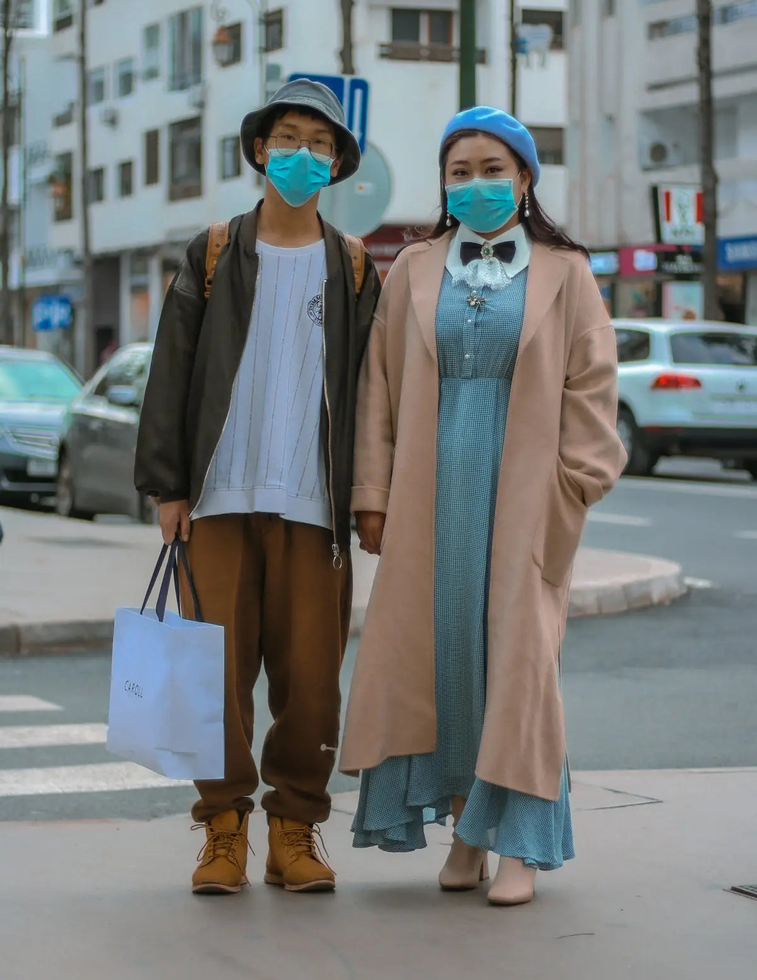 woman in blue dress and white cardigan holding white paper bag