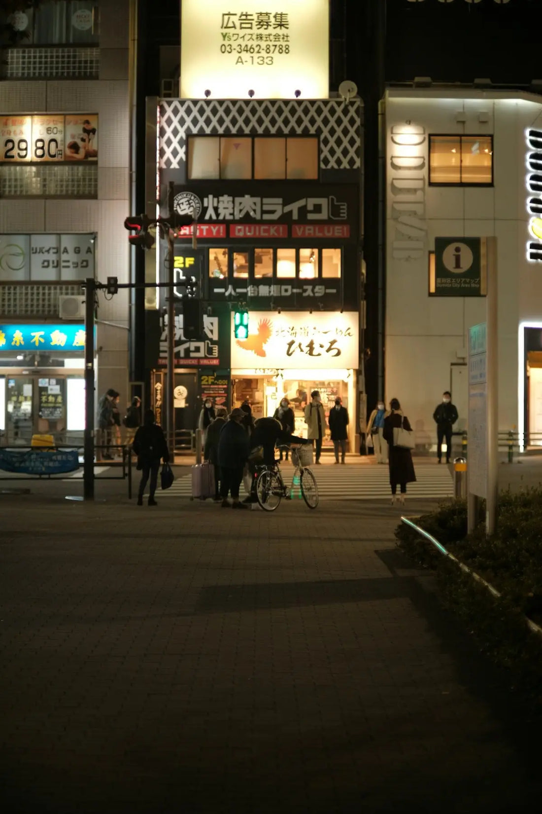 a group of people walking down a street at night