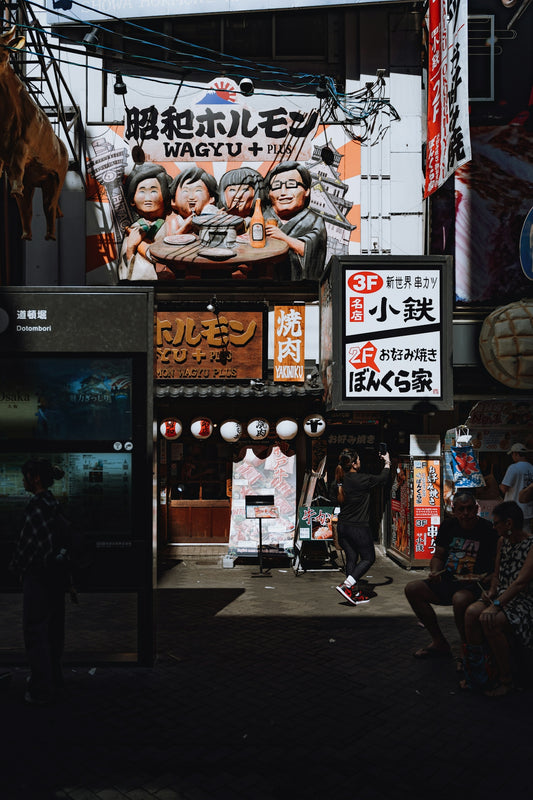 A group of people walking down a street next to tall buildings