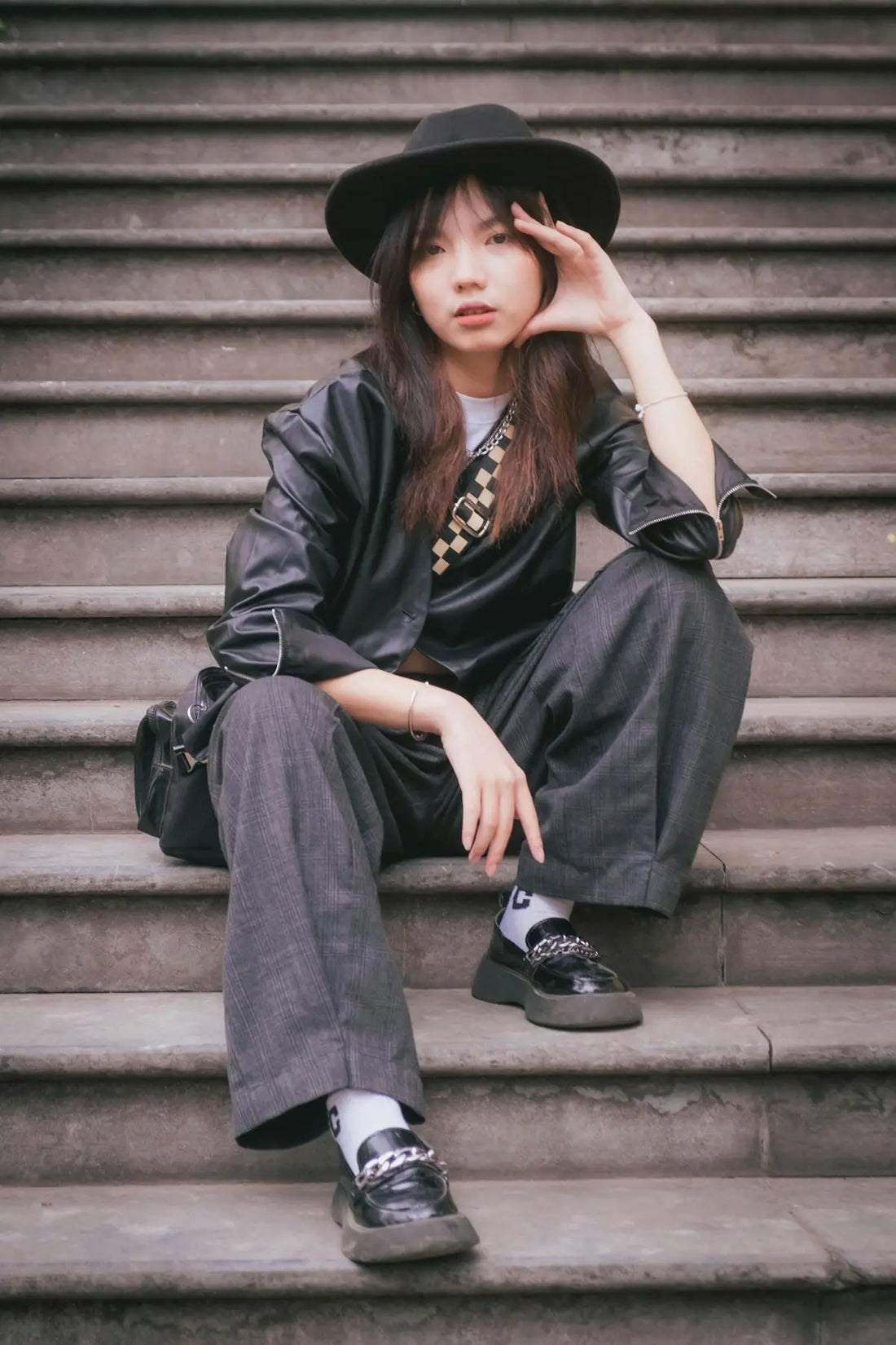 a woman sitting on steps wearing a black hat